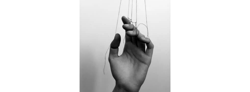 la_communication_perverse main tenue par des fils à chaque doigt, comme une marionnette